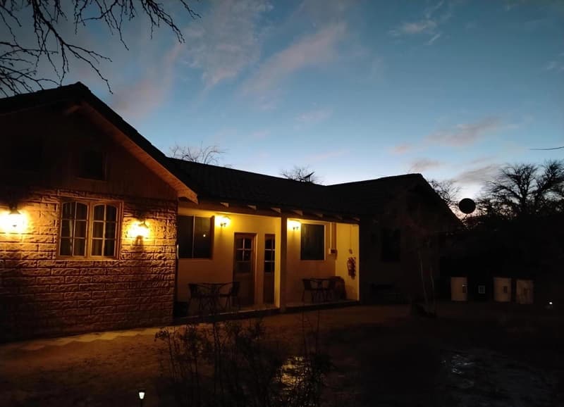 Cabins at dusk, with a snow-capped volcano behind them and an orange sky.